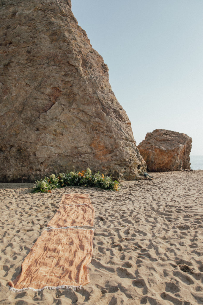 Ceremony spot on the beach with garland and towels to walk on