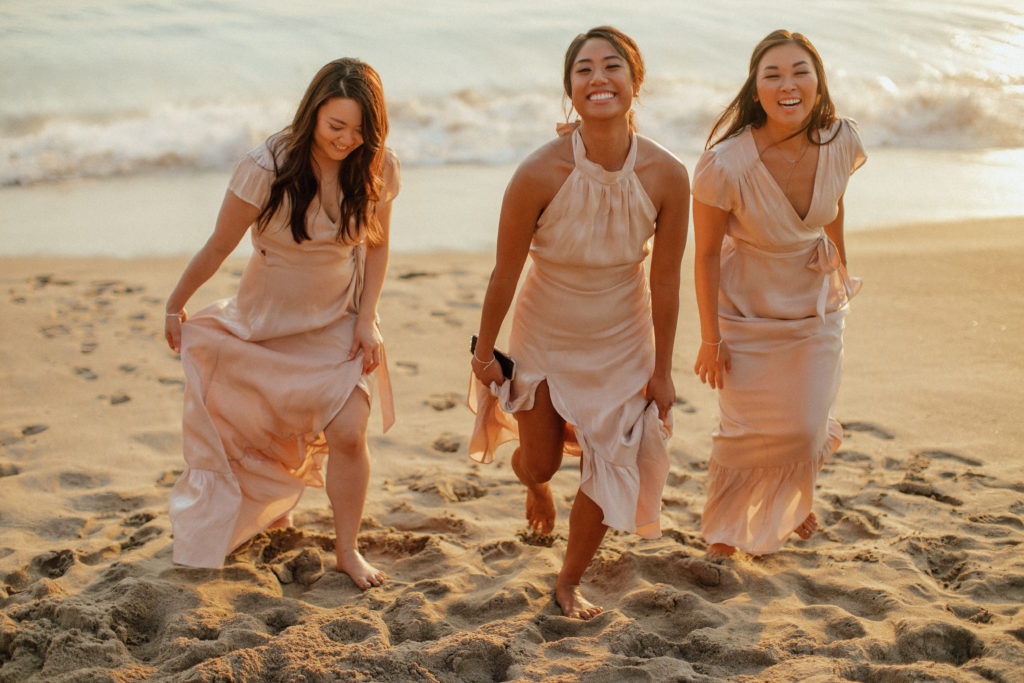 The bridesmaids laughing and running on the beach